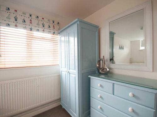 a bathroom with a blue dresser and a mirror at Kittiwake in Crantock