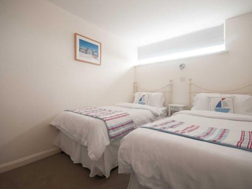 two beds in a room with white walls at Kittiwake in Crantock