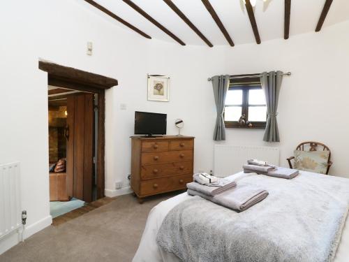 a bedroom with a bed and a dresser and a television at Harbourne Oast in Tenterden