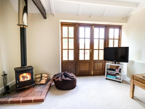 a living room with a wood stove and a tv at Cheshire Cheese Cottage in Chester