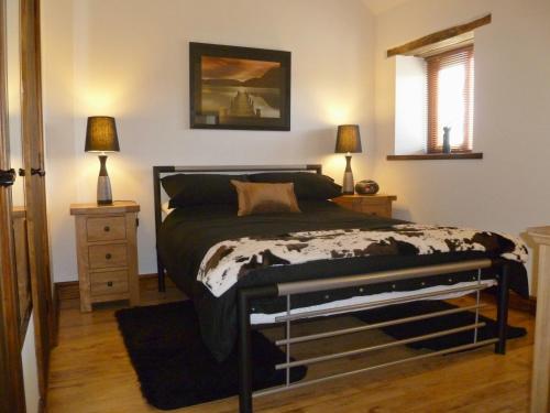 a bedroom with a bed and two lamps and a window at Daisy Cottage in Penrith