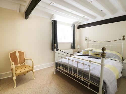 a bedroom with a bed and a chair and a window at Cheshire Cheese Cottage in Chester
