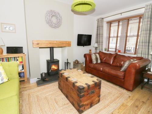 a living room with a leather couch and a fireplace at Llwyn Onn in Dolwyddelan