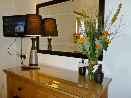 uma cómoda com um candeeiro e flores sobre ele em Daisy Cottage em Penrith
