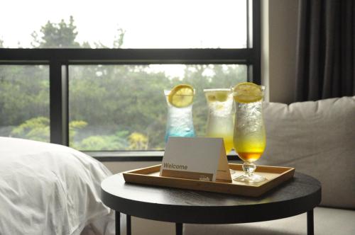 a tray with two glasses and a laptop on a table at Hotel Nanta Jeju in Jeju