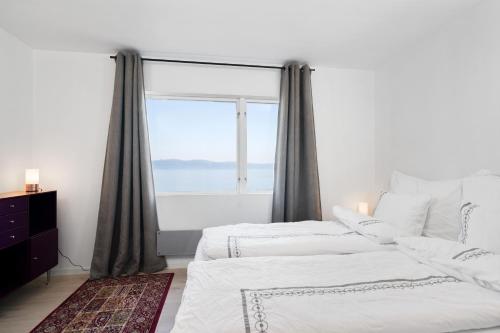 two beds in a bedroom with a large window at Private House & Bungalow by the sea in Trondheim