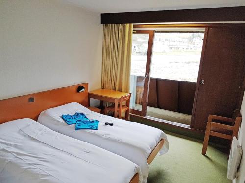 une chambre d'hôtel avec un lit et une serviette bleue. dans l'établissement Le Village Vacances de Luz Saint Sauveur, à Luz-Saint-Sauveur