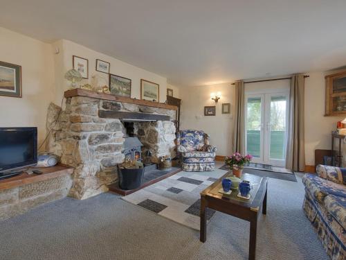 a living room with a stone fireplace and a tv at The Annexe, Higher Lydgate Farmhouse in Postbridge
