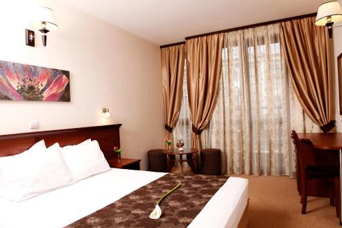 a hotel room with a bed and a desk and curtains at Favorit Hotel in Sofia