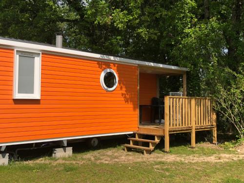 pomarańczowy domek z werandą i oknem w obiekcie Camping Fleur d'Oleron w mieście Saint-Pierre-dʼOléron