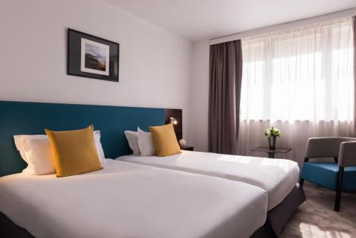 a hotel room with two beds and a window at Best Western Hotel le Galice Aix-en-Provence in Aix-en-Provence