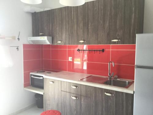 a kitchen with a sink and red tile on the wall at City Apartment in Ierapetra
