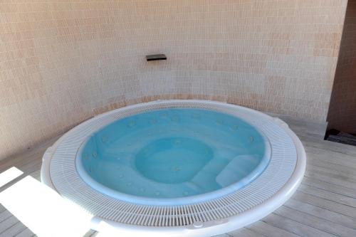 a blue tub in a bathroom with a tile wall at Hotel Acqui & Centro Benessere in Acqui Terme