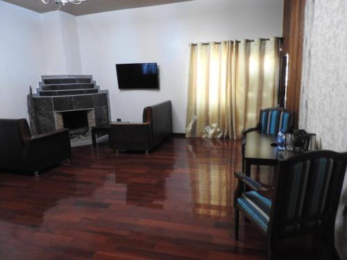 a living room with a fireplace and a tv at Misty Mountain Lodge in Naro Moru