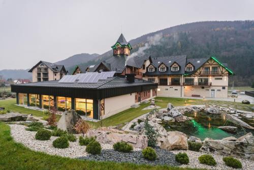 a large house with a pond in front of it at Village Resort Hanuliak in Terchová