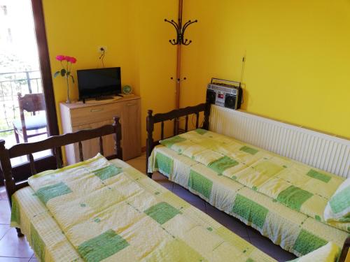 two beds in a room with yellow walls at Smeštaj - sobe MARVEL in Niš