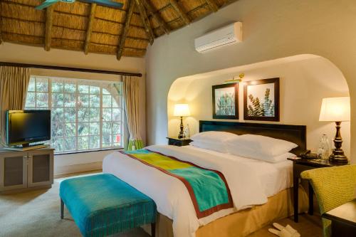 a bedroom with a large bed and a television at Mount Grace Hotel & Spa in Magaliesburg