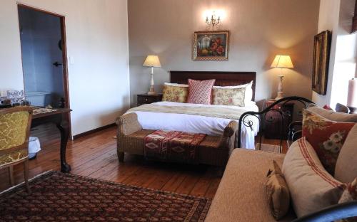 a bedroom with a bed and a chair and a couch at New Stone Manor in Mossel Bay