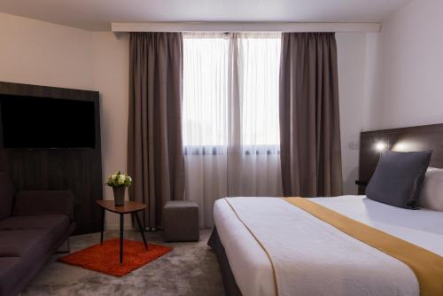 a hotel room with a bed and a couch at Best Western Hotel le Galice Aix-en-Provence in Aix-en-Provence