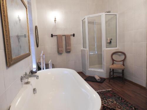 ein weißes Bad mit einer Badewanne und einer Dusche in der Unterkunft New Stone Manor in Mossel Bay