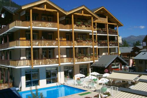 - un grand bâtiment avec une piscine en face dans l'établissement Hôtel Le Grand-Bec, à Pralognan-la-Vanoise