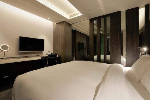 a bedroom with a white bed and a television at Starhaus Hotel in Kaohsiung
