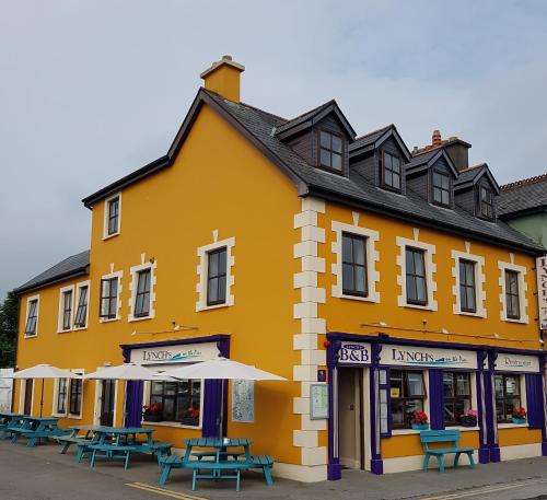 a yellow building with tables and umbrellas on a street at Lynch's on the Pier in Castletownbere