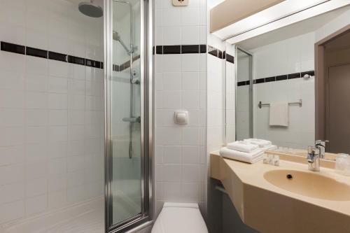 uma casa de banho com um lavatório e um chuveiro em The Originals City, Tabl'Hôtel, Amiens em Longueau