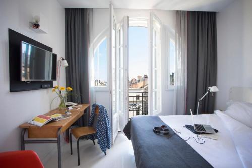 a hotel room with a bed and a desk and a window at Collège Hôtel in Lyon