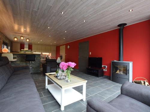 un soggiorno con pareti rosse e un tavolo con fiori di Chic Holiday Home in Noville with Sauna a Noville