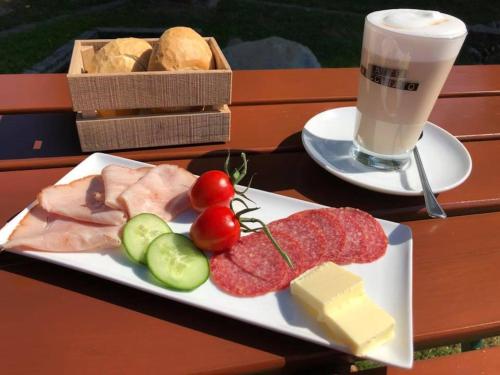 a plate of food with meat and cheese and a drink at Stücklhof Eurasburg in Eurasburg