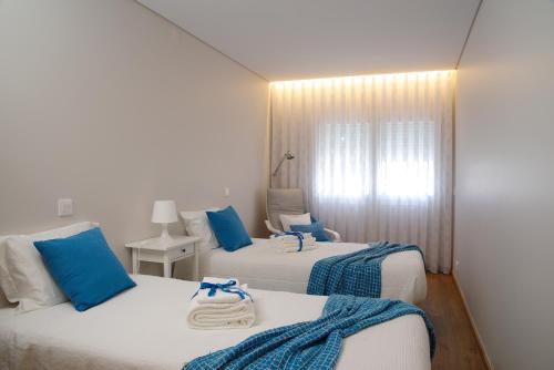 two beds in a room with blue and white at A Nossa Praia in Praia da Barra