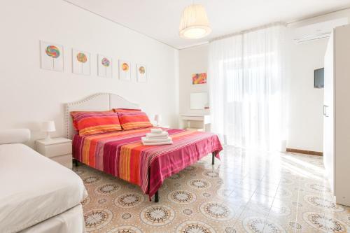een witte slaapkamer met een bed met een kleurrijke deken bij casa giò giò in Sorrento