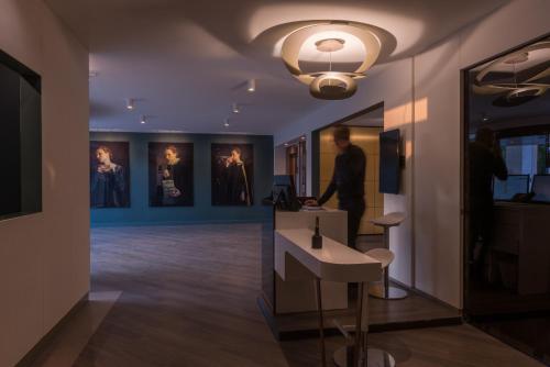 a man standing in a room with paintings on the walls at Best Western Hotel le Galice Aix-en-Provence in Aix-en-Provence