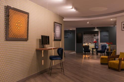 a waiting room with chairs and a tv on a wall at Best Western Hotel le Galice Aix-en-Provence in Aix-en-Provence