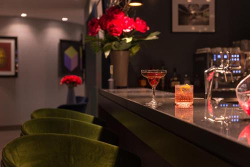 a bar with green chairs and a counter with wine glasses at Best Western Hotel le Galice Aix-en-Provence in Aix-en-Provence