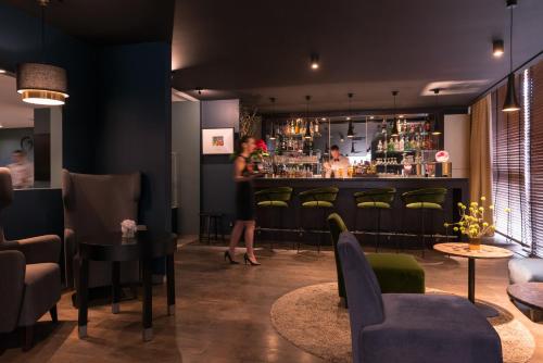 a woman standing at a bar in a restaurant at Best Western Hotel le Galice Aix-en-Provence in Aix-en-Provence