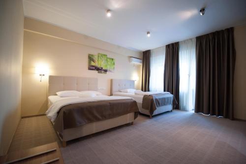 um quarto de hotel com duas camas e uma janela em Bruxelles Guesthouse Craiova em Craiova