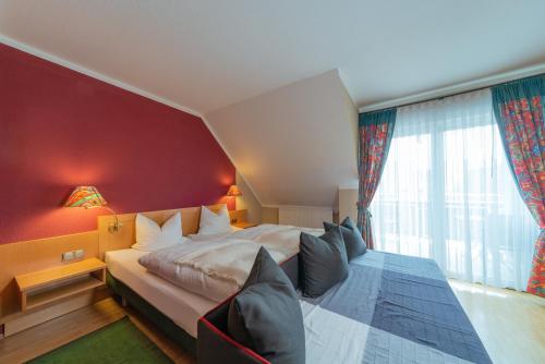 um quarto com uma cama grande e uma parede vermelha em Wirtshaus & Hotel Zur Alten Brauerei Zapf em Uettingen