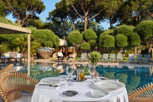 a table with wine glasses next to a swimming pool at Villa Duflot Hôtel & Spa Perpignan in Perpignan