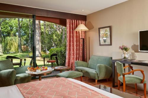 a hotel room with a bed and chairs and a table at Villa Duflot Hôtel & Spa Perpignan in Perpignan