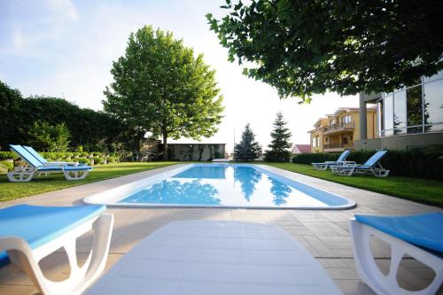 une piscine avec des chaises longues et une maison dans l'établissement Bruxelles Guesthouse Craiova, à Craiova