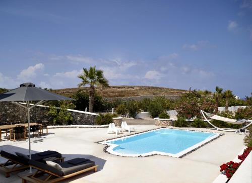 a swimming pool with chairs and an umbrella at Amor Hideaway Villas in Fira