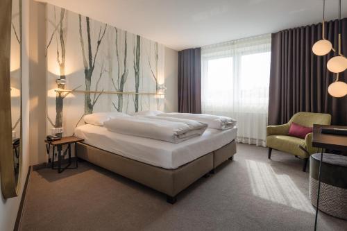 a bedroom with a large bed and a chair at Parkhotel Schmid in Adelsried