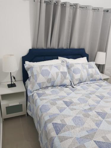 łóżko z niebiesko-białą kołdrą i poduszkami w obiekcie KSL Residence w mieście Boca Chica