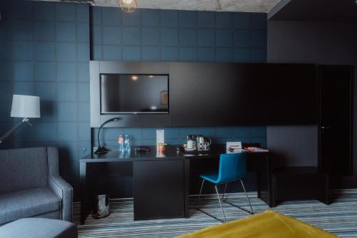 a room with a desk with a chair and a tv at Aparthotel Tangerine in Batumi