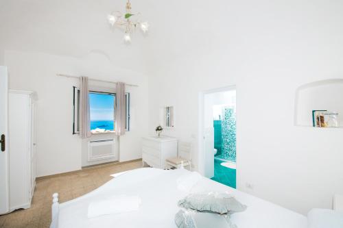 Habitación blanca con cama y ventana en La Borragine Apartament en Positano