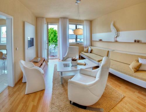 ein Wohnzimmer mit weißen Stühlen und einem Sofa in der Unterkunft Apartments in Warnemuende in Warnemünde