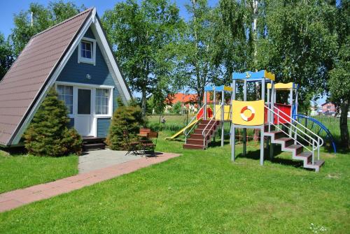a playground in front of a house with a slide at Camping Marco Polo in Łeba