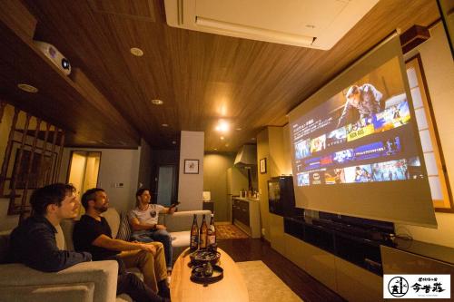 a group of people sitting in a living room watching a tv at KONJAKUSO Osaka Dotonbori "YORIAI" Penthouse Stay in Osaka